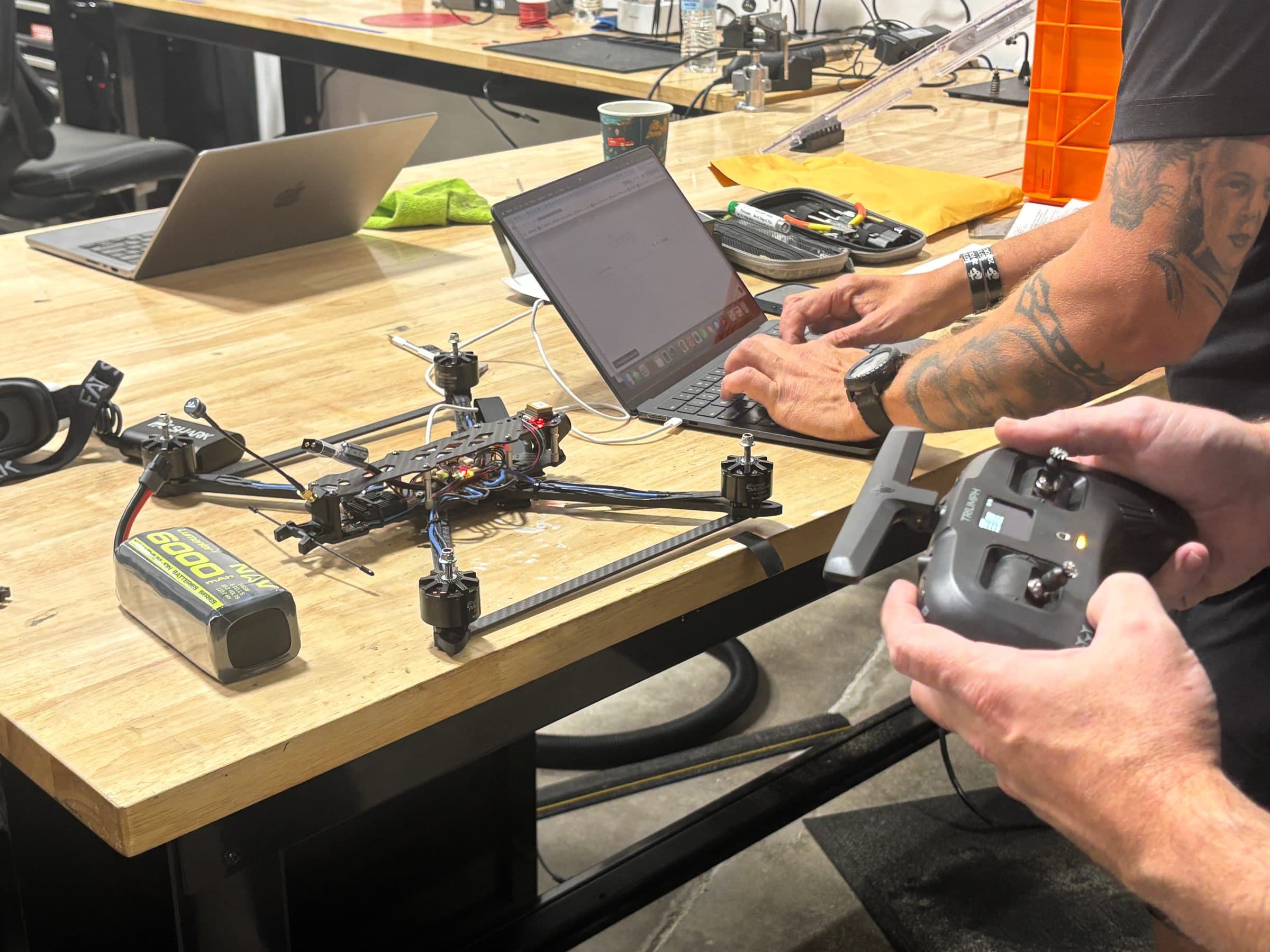 An engineer testing an FPV drone at a bench, transmitter in hand