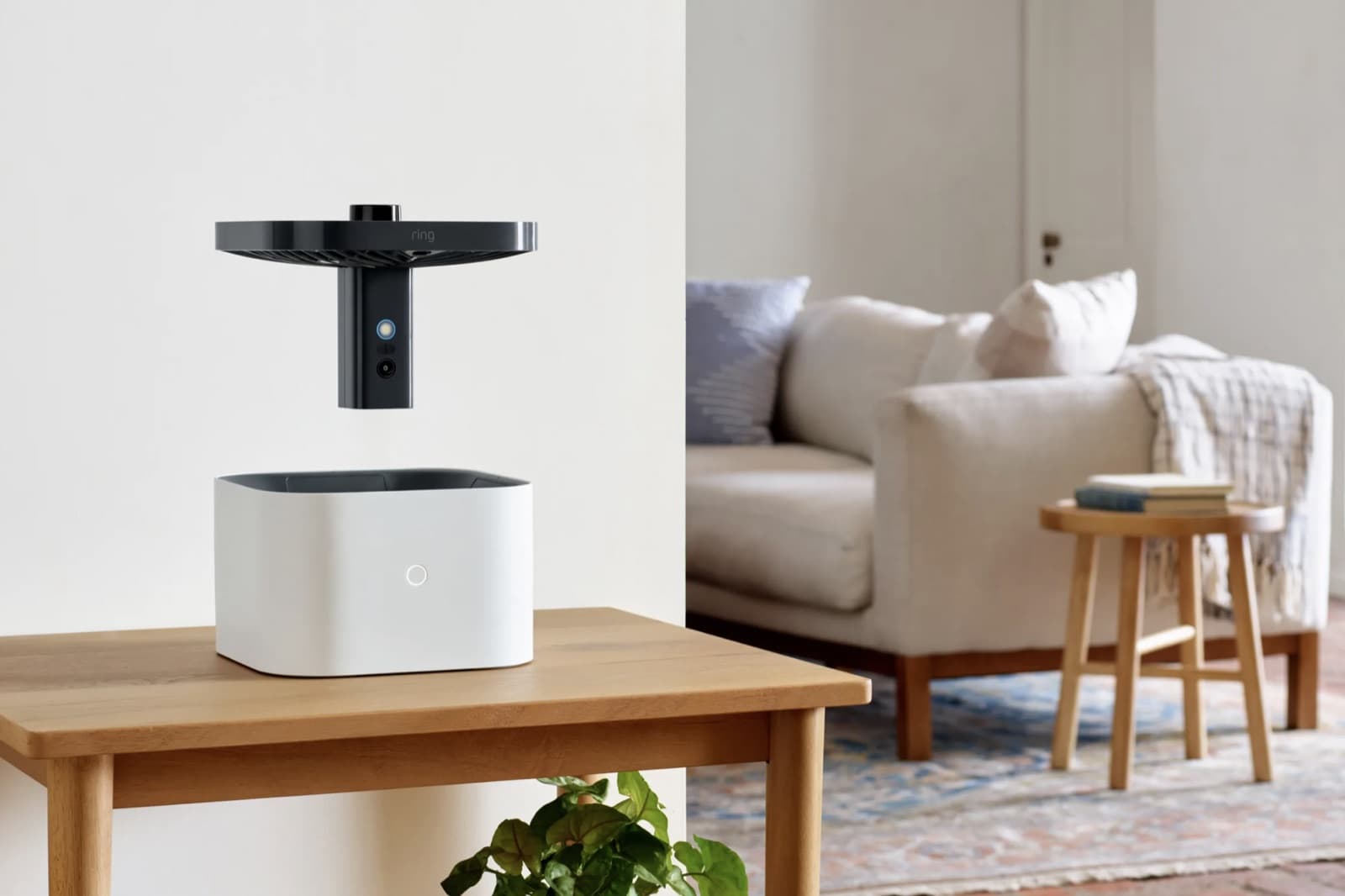 The Ring Always Home Cam, a small black indoor drone, hovering above its white dock on a living-room table